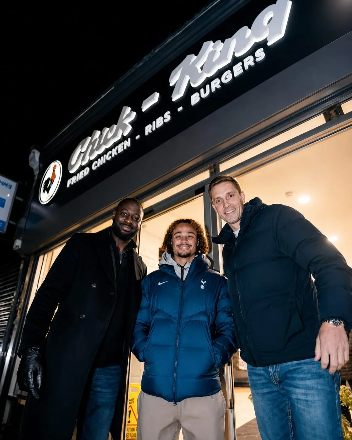 Three visitors posing together outside the shop on a matchday evening