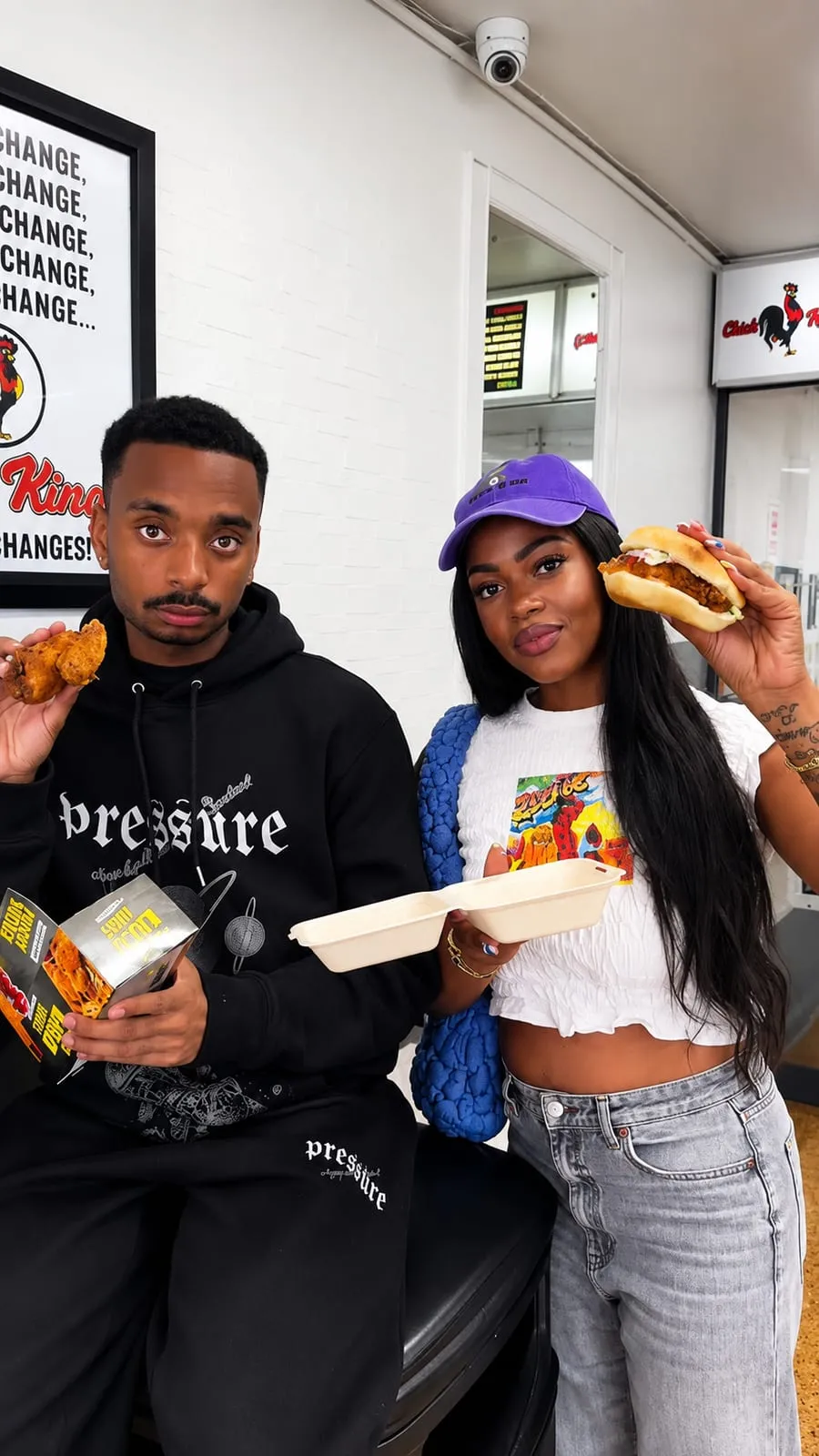 Two customers holding chicken and a burger inside the shop
